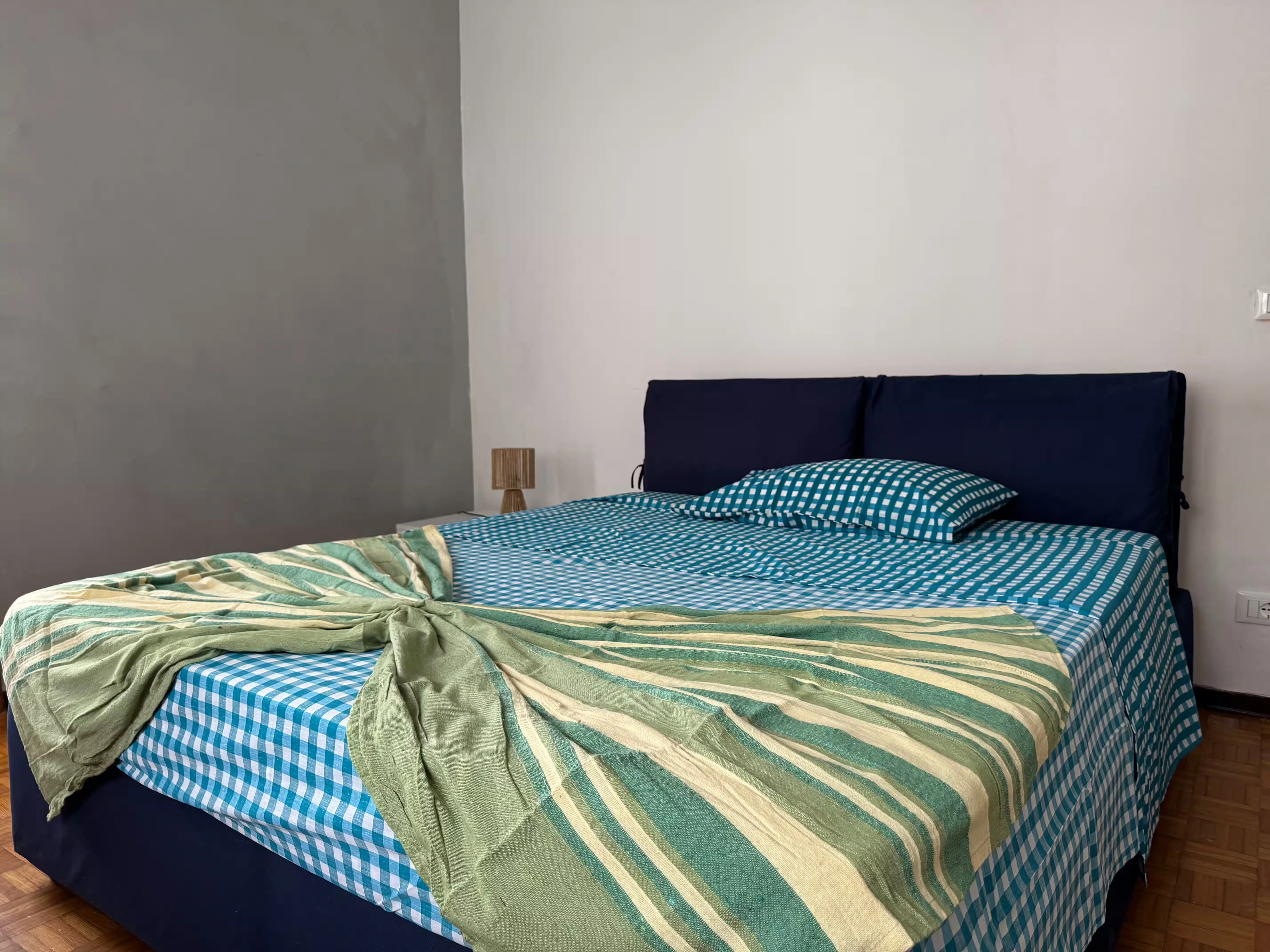 Camera matrimoniale con letto a quadretti azzurri e plaid verde - Villa Sole Casa Famiglia Roasio